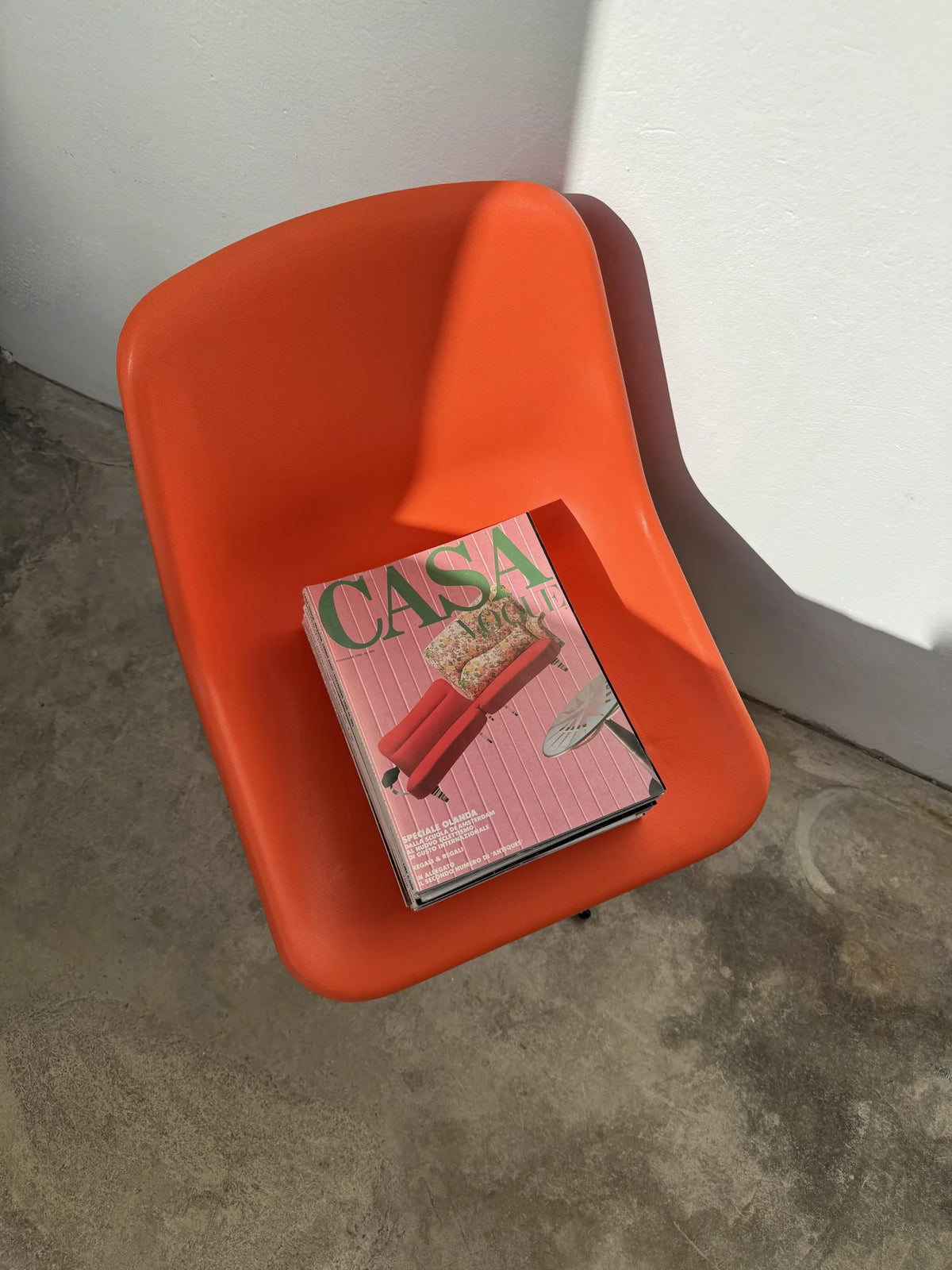 Sedia girevole plastica arancione di Robin Day per Tecno – con pila di riviste Vogue Casa d'epoca