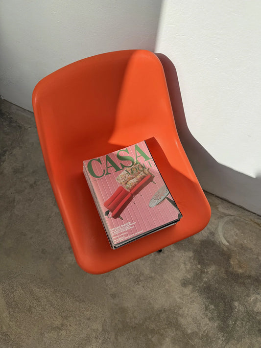 Sedia girevole plastica arancione di Robin Day per Tecno – con pila di riviste Vogue Casa d'epoca