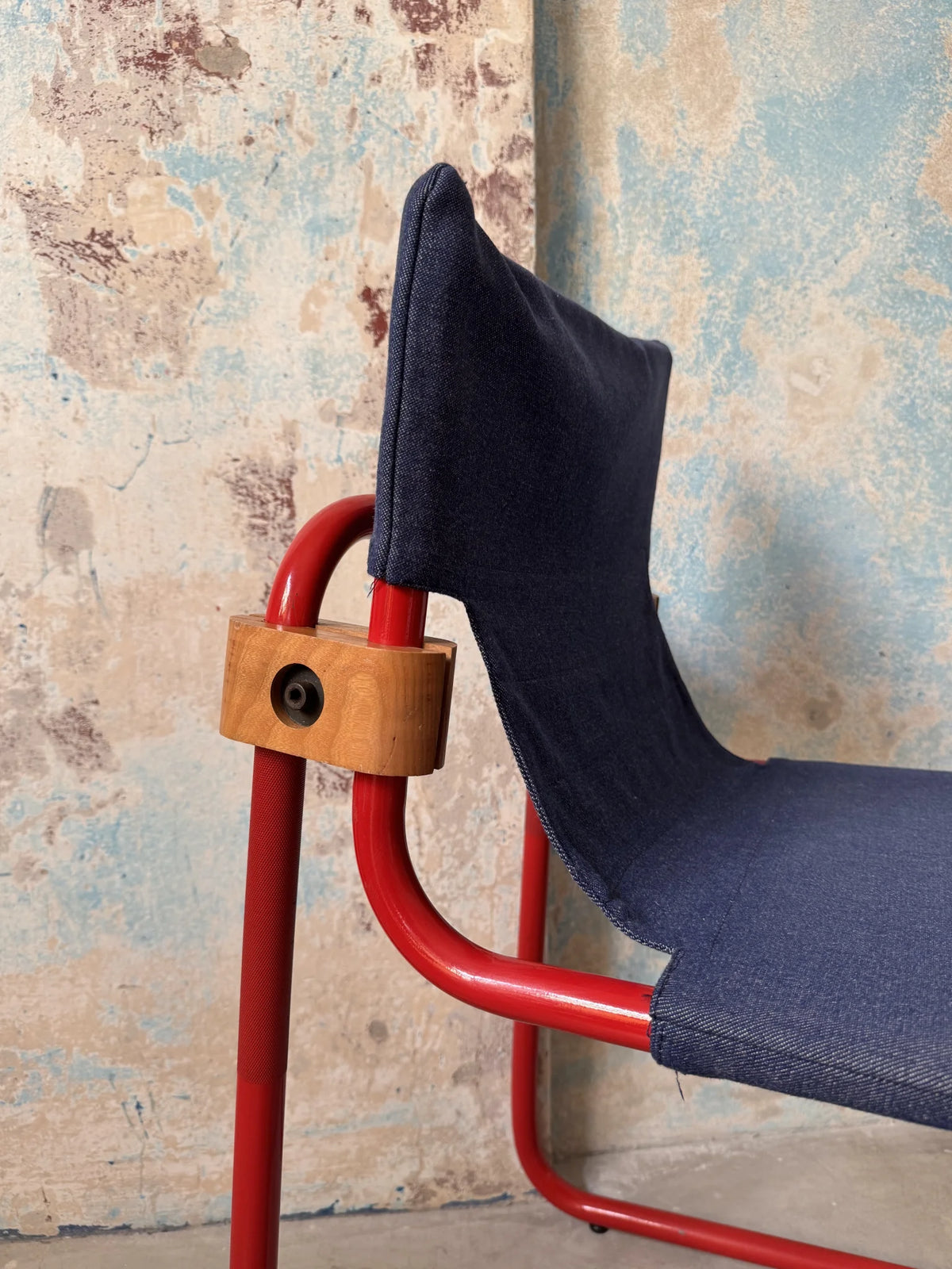 Sedia in metallo rosso con seduta in denim – dettaglio attacco laterale in legno e metallo