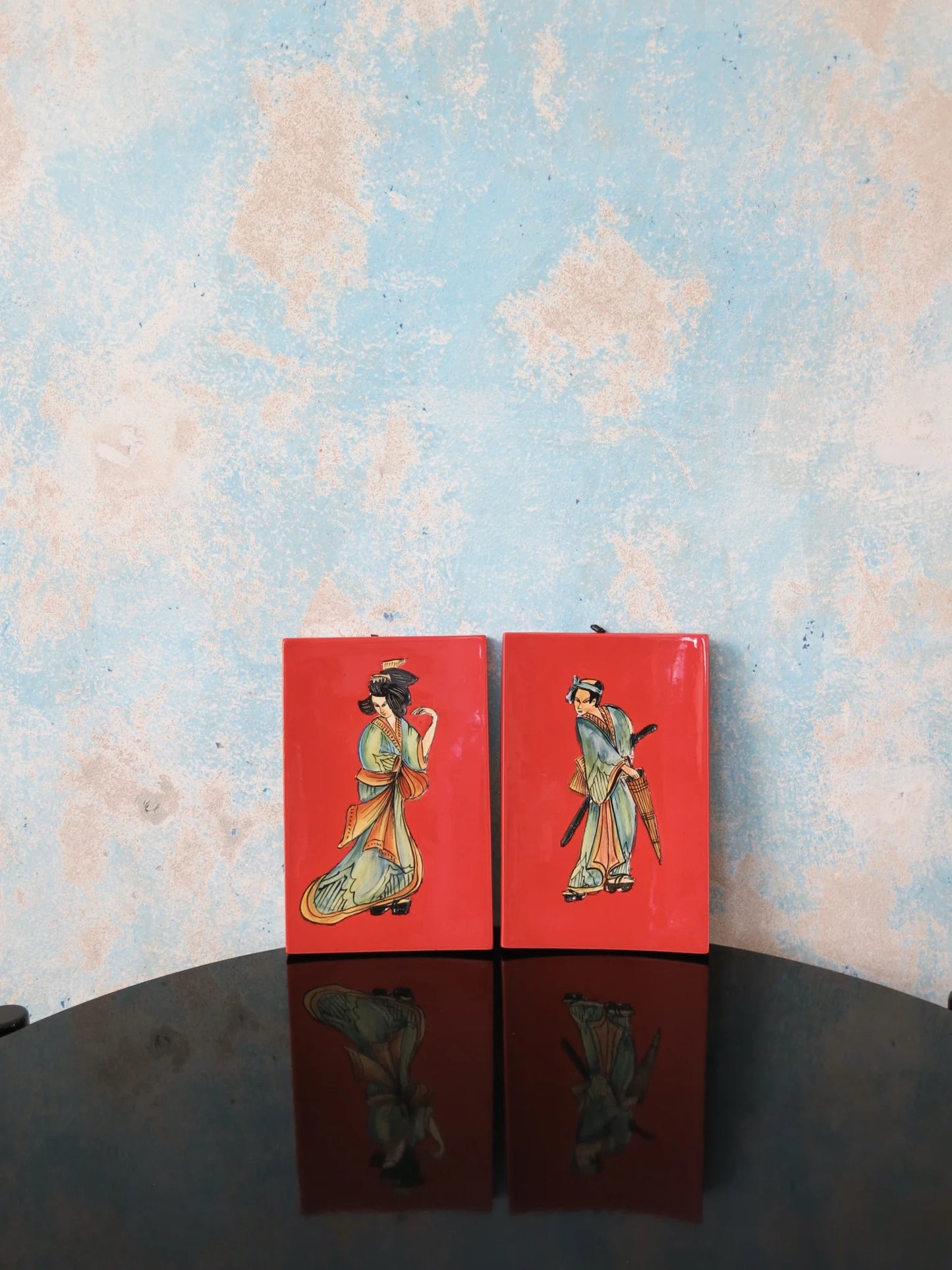 Coppia mattonelle ceramica smaltata S.I.C.A.S Firenze – figure orientali su fondo rosso, su tavolo nero con riflesso