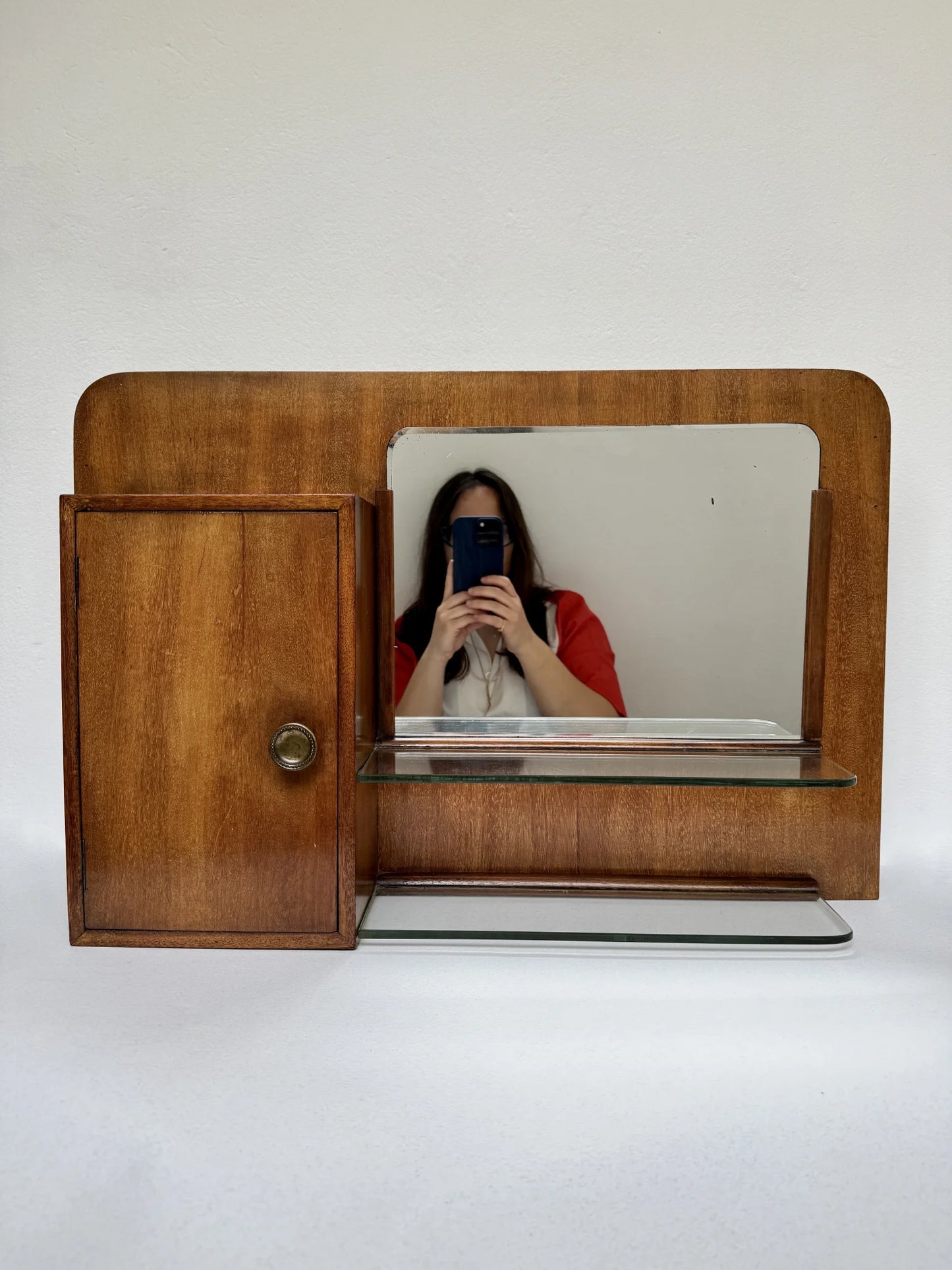 Stipetto da parete in legno noce anni '40 – vista frontale con specchio, mensola in vetro e sportello laterale, con riflesso donna