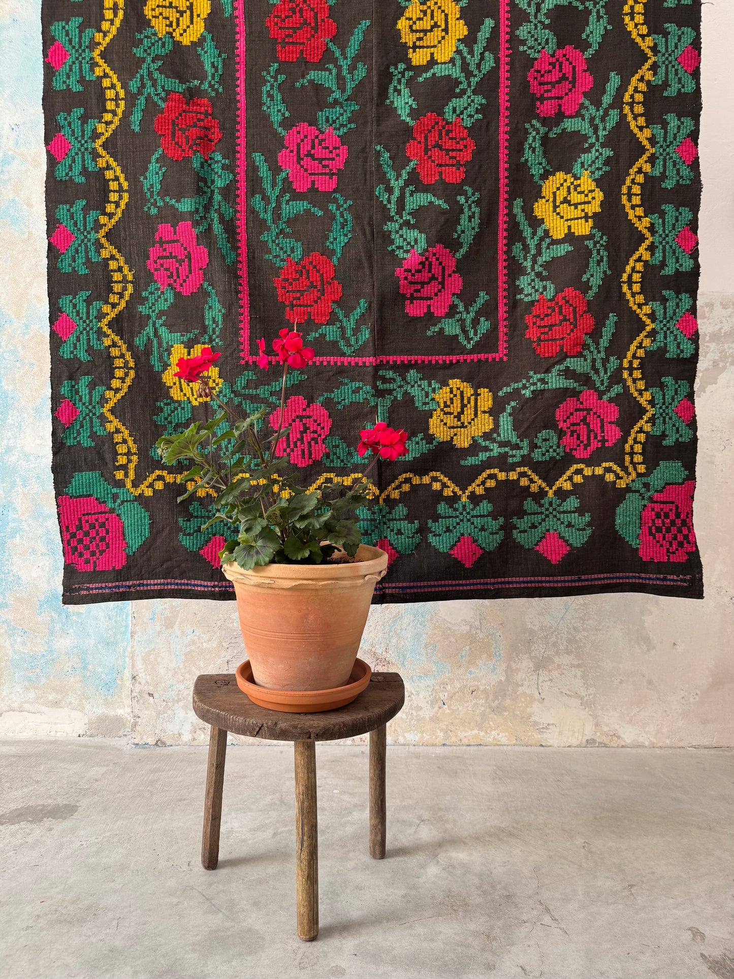 Tappeto ricamato a mano su fondo nero – vista a metà con rose colorate e pianta fiorita in vaso davanti