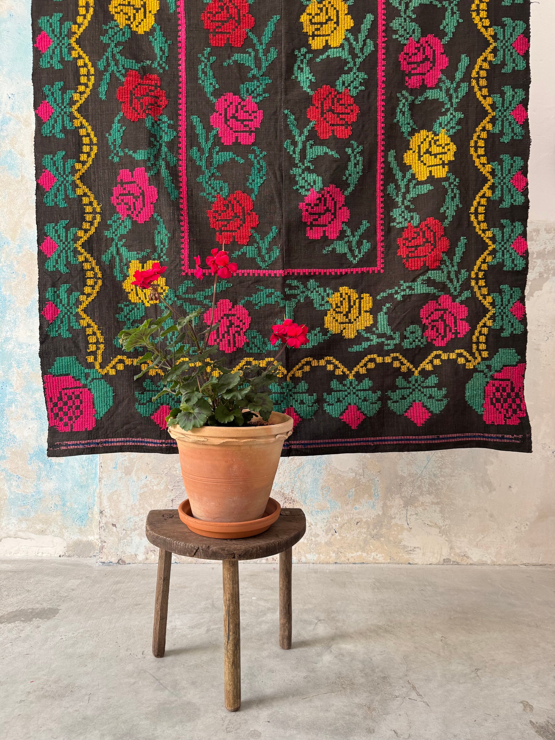 Tappeto ricamato a mano su fondo nero – vista a metà con rose colorate e pianta fiorita in vaso davanti