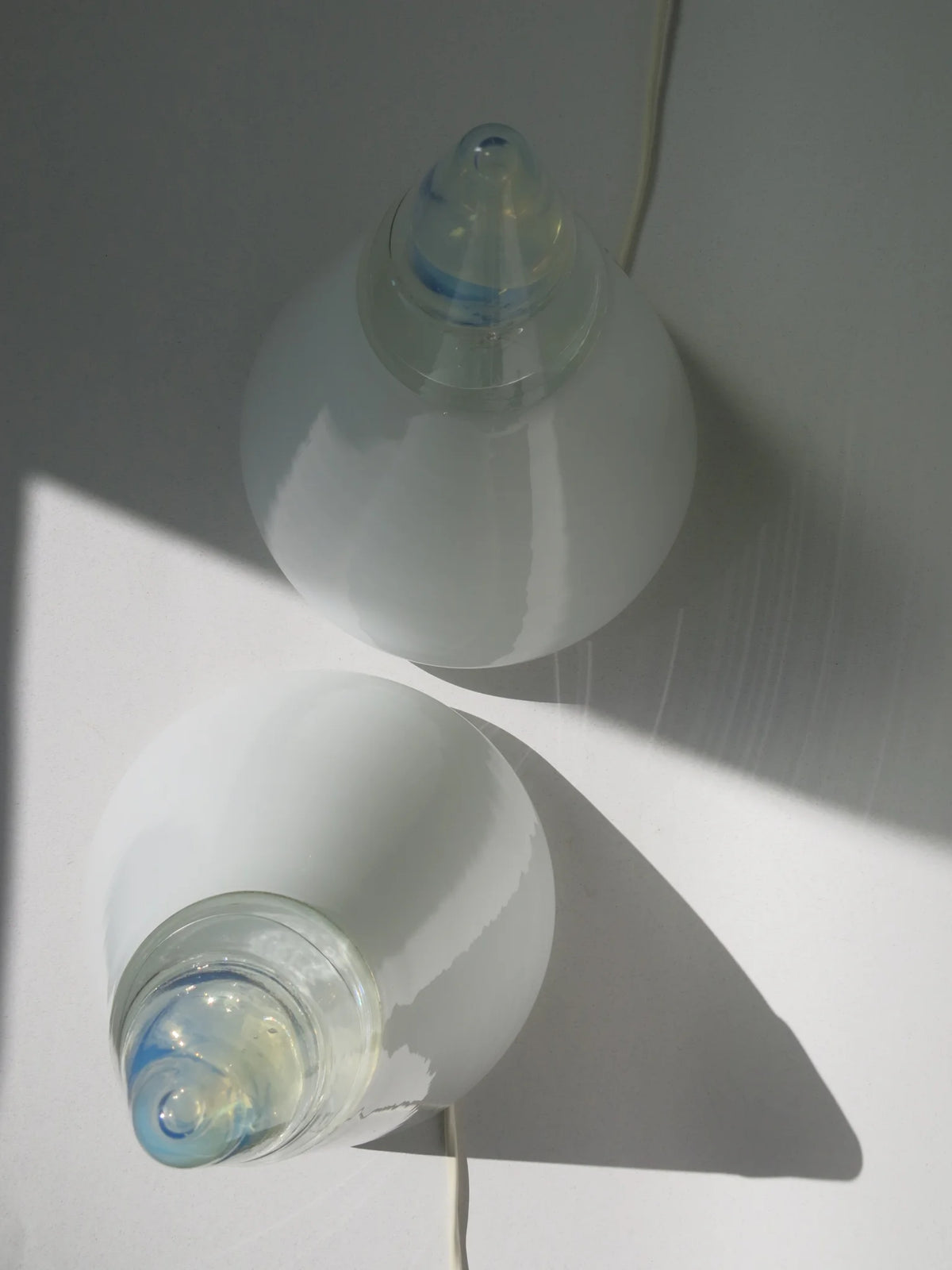 Coppia lampade coniche in vetro bianco Leucos – viste dall'alto con riflessi di luce