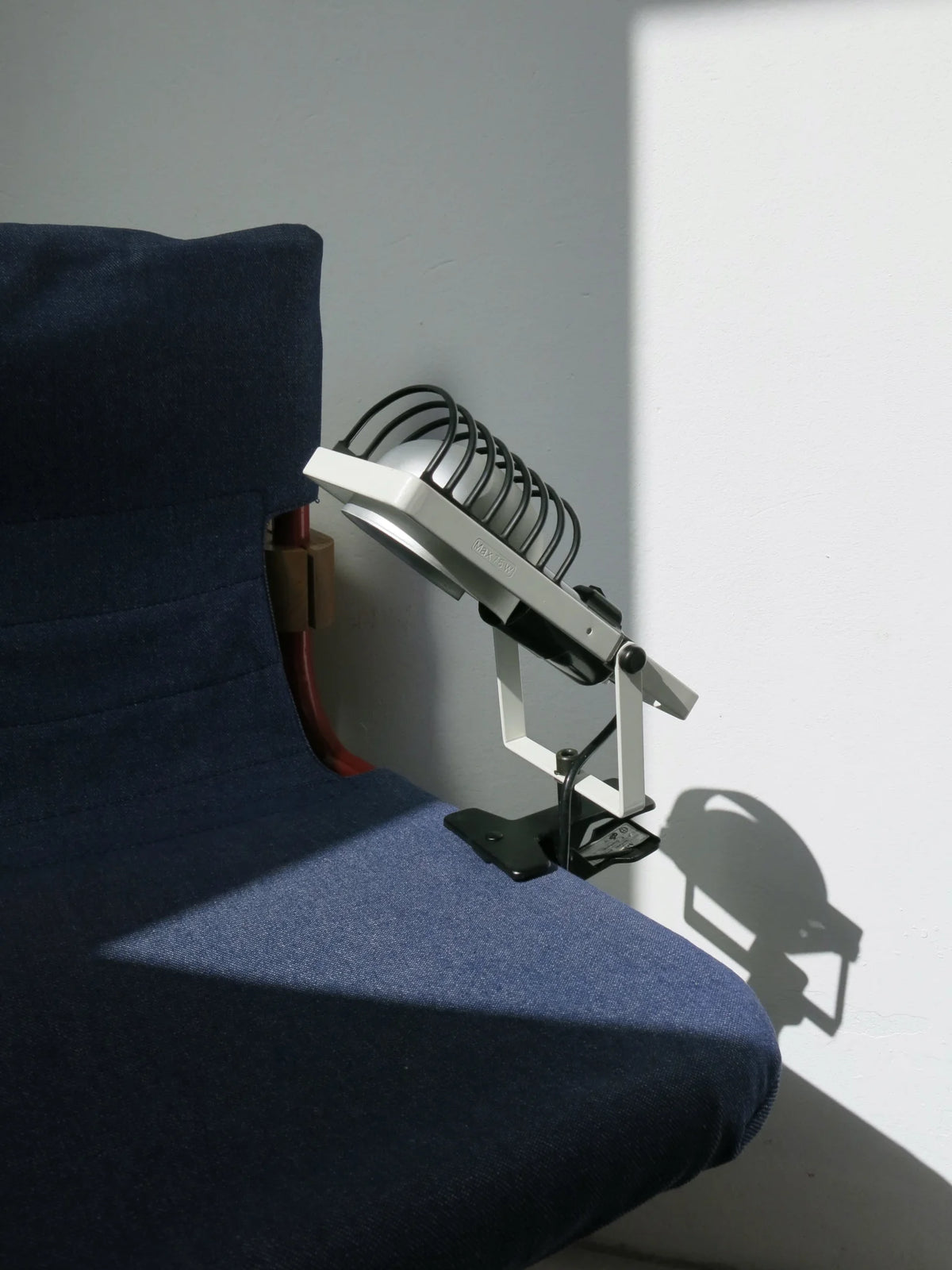 Lampada faretto con morsetto Sintesi di Artemide – attaccata alla seduta di una sedia, colore bianco, vista dal lato