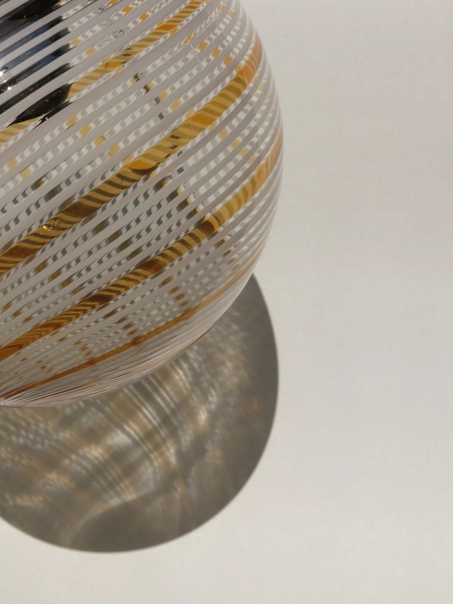 Lampadario di Murano a sfera in vetro soffiato – vista laterale con filigrana a spirale bianca e oro, luce naturale