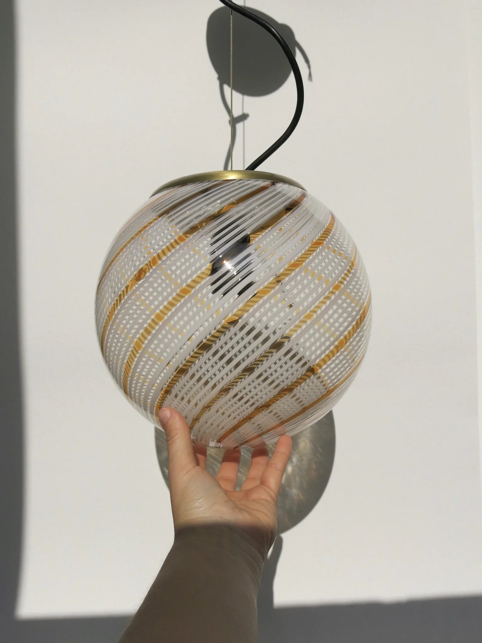Lampadario di Murano a sfera in vetro soffiato – in mano per mostrare le proporzioni, filigrana a spirale bianca e oro