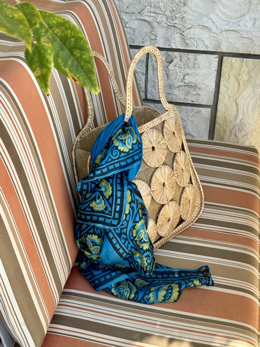 Borsa in paglia con intreccio di cerchi – appoggiata su un divanetto con foulard blu