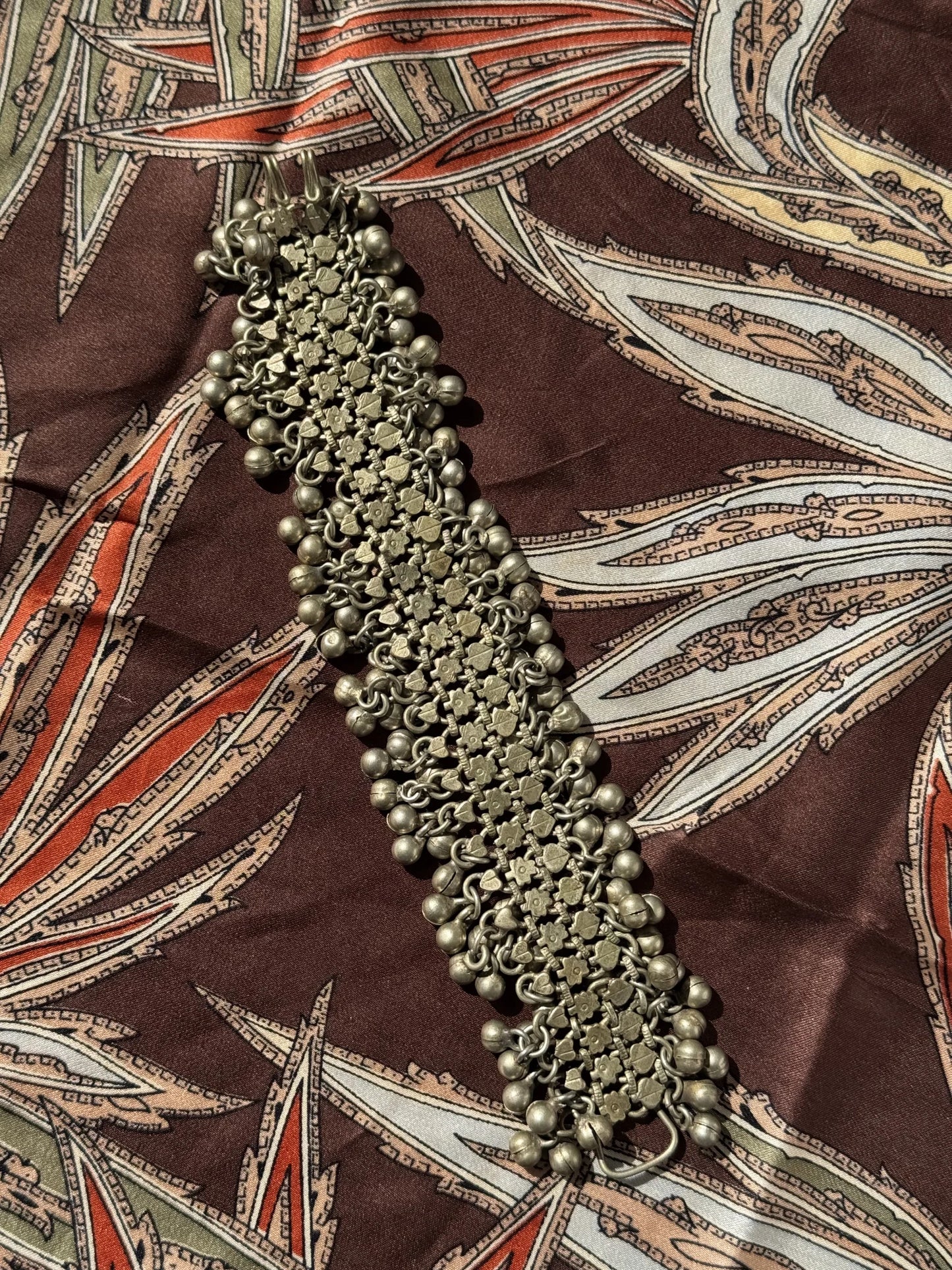 Bracciale metallo indiano con sonagli – nella sua interezza su una stoffa di seta