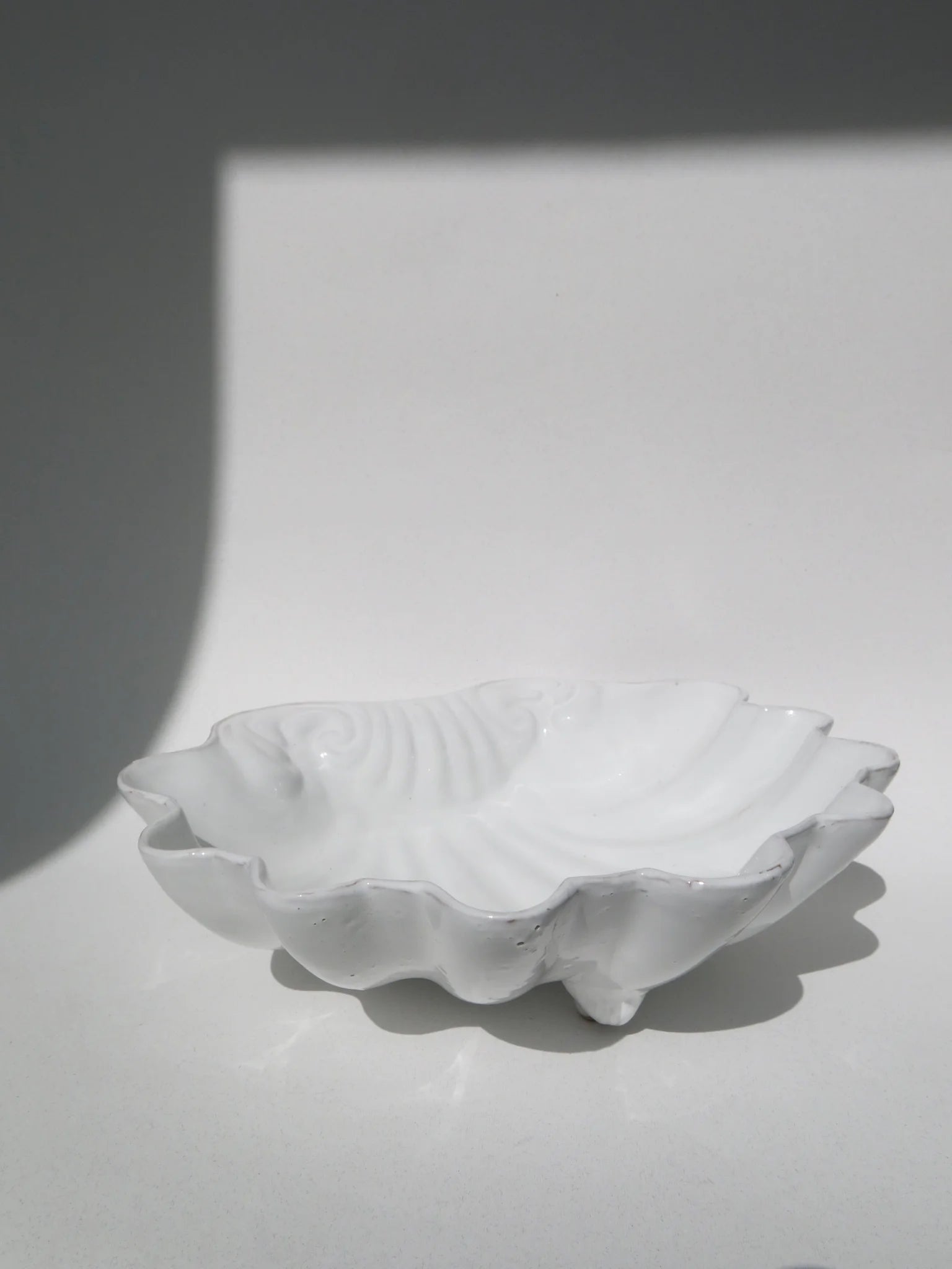 Ciotola a forma di conchiglia in ceramica bianca – vista dal lato con piedini