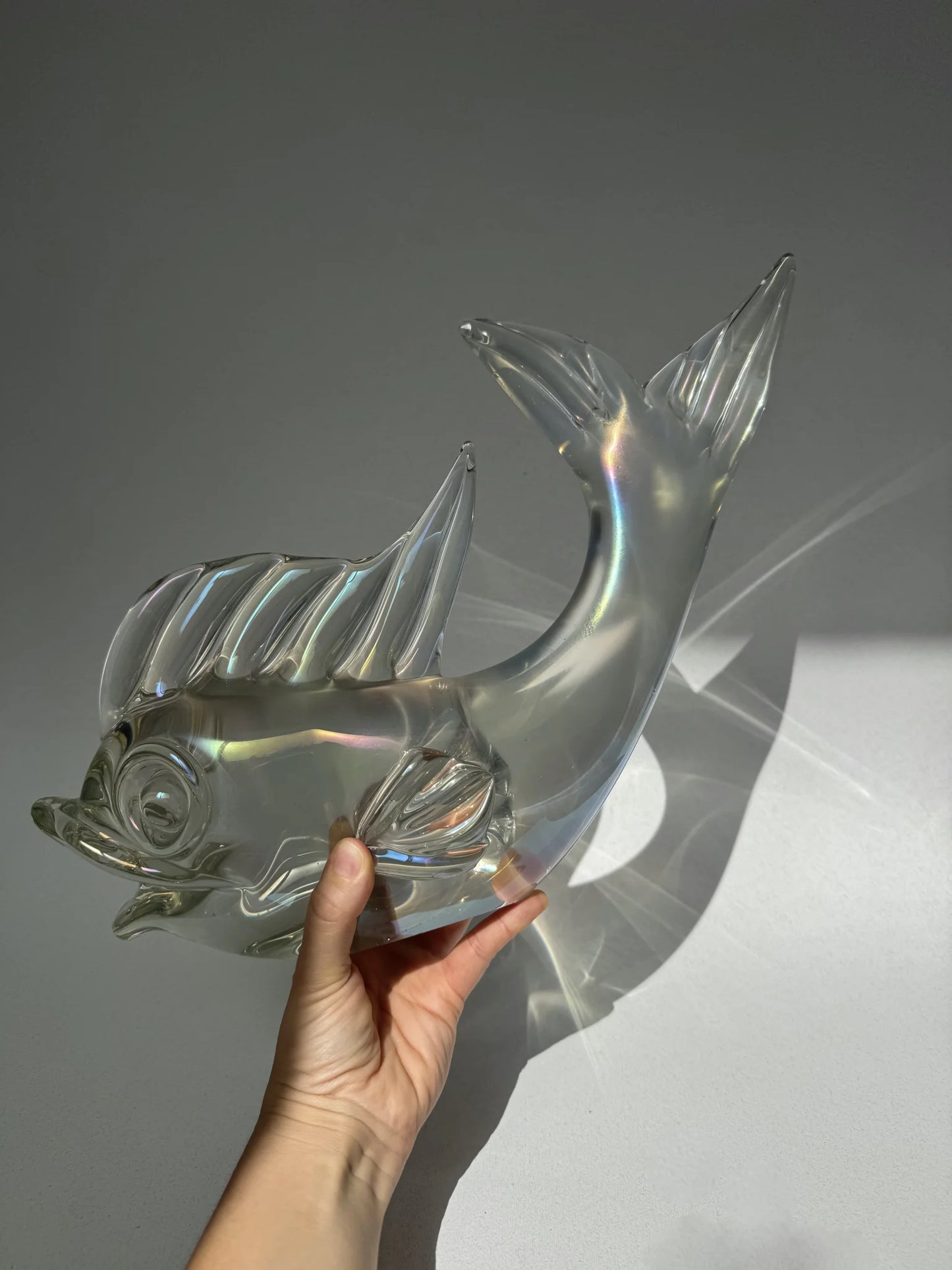 Grande pesce in vetro di Murano perlescente – tenuto in mano con riflessi di luce