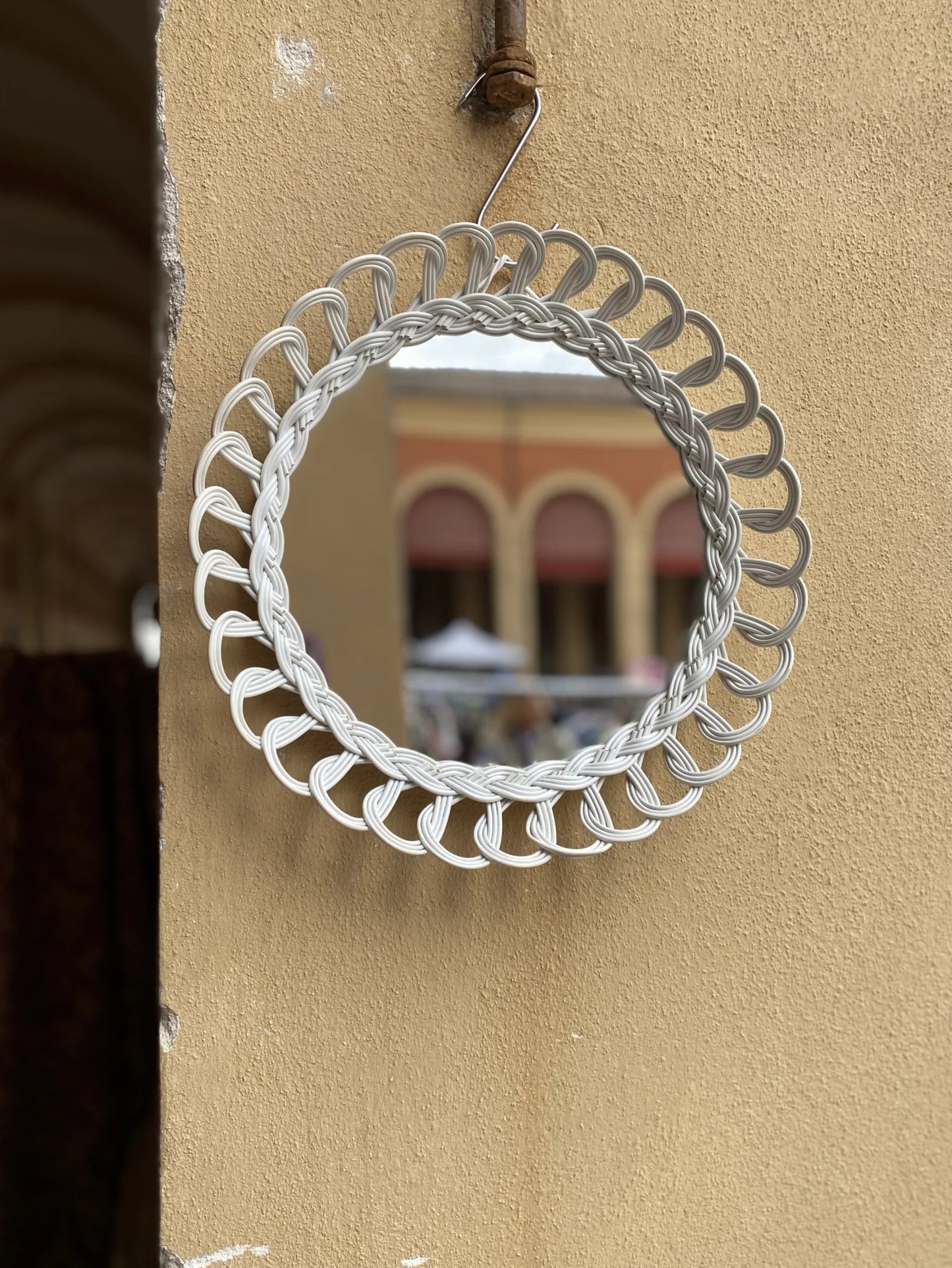 Specchio rotondo con cornice in plastica intrecciata bianca – appeso su muro esterno colore terra bruciata, anni '60