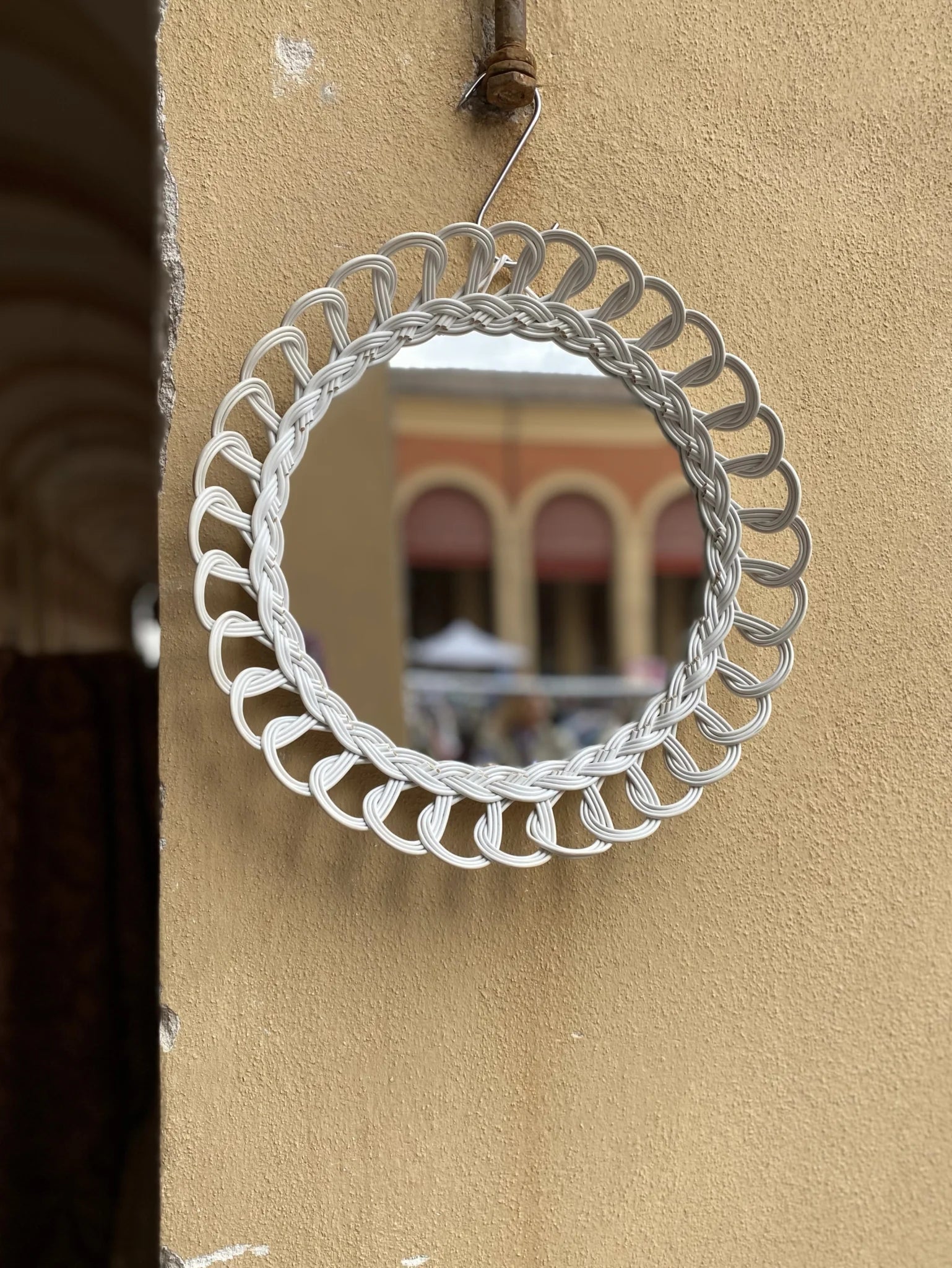Specchio rotondo con cornice in plastica intrecciata bianca – appeso su muro esterno colore terra bruciata, anni '60