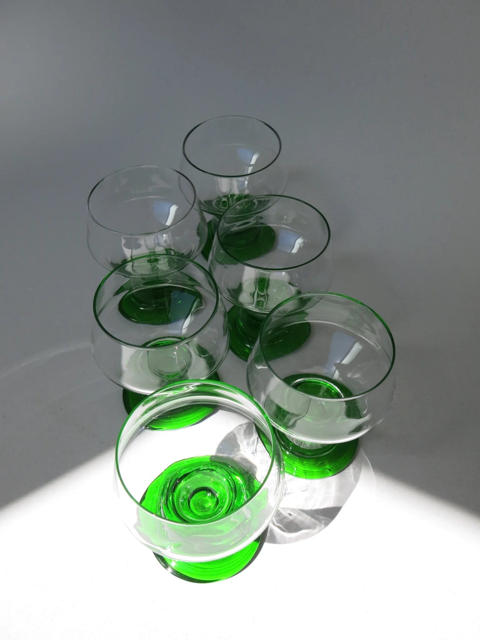 Bicchieri da acqua in vetro – dettaglio stelo e base verde smeraldo, luce radente con ombre