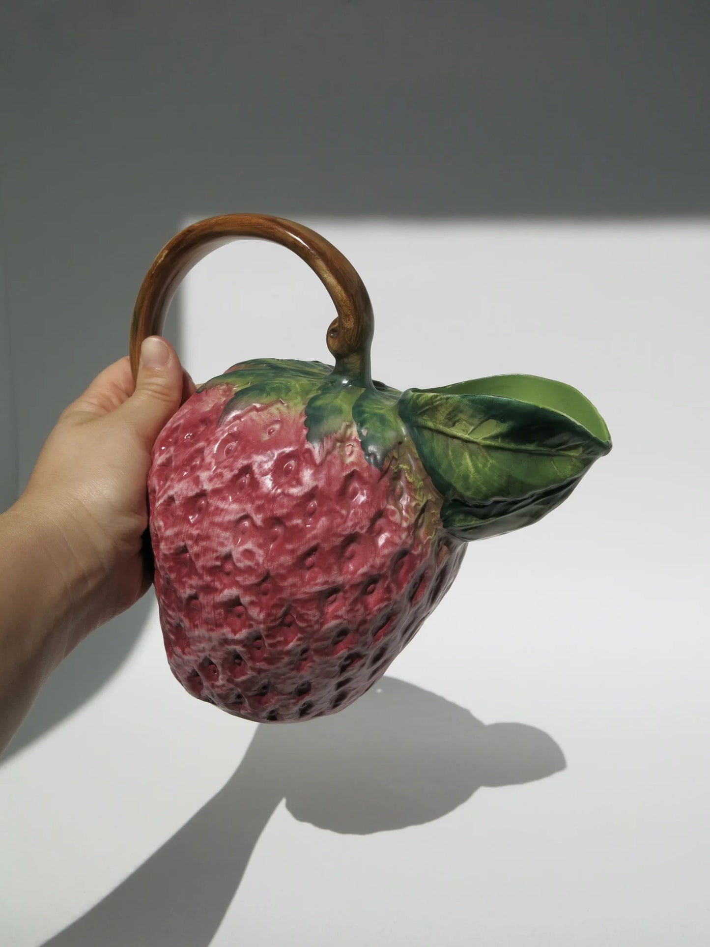 Brocca ceramica a forma di fragola – vista completa, tenuta in mano