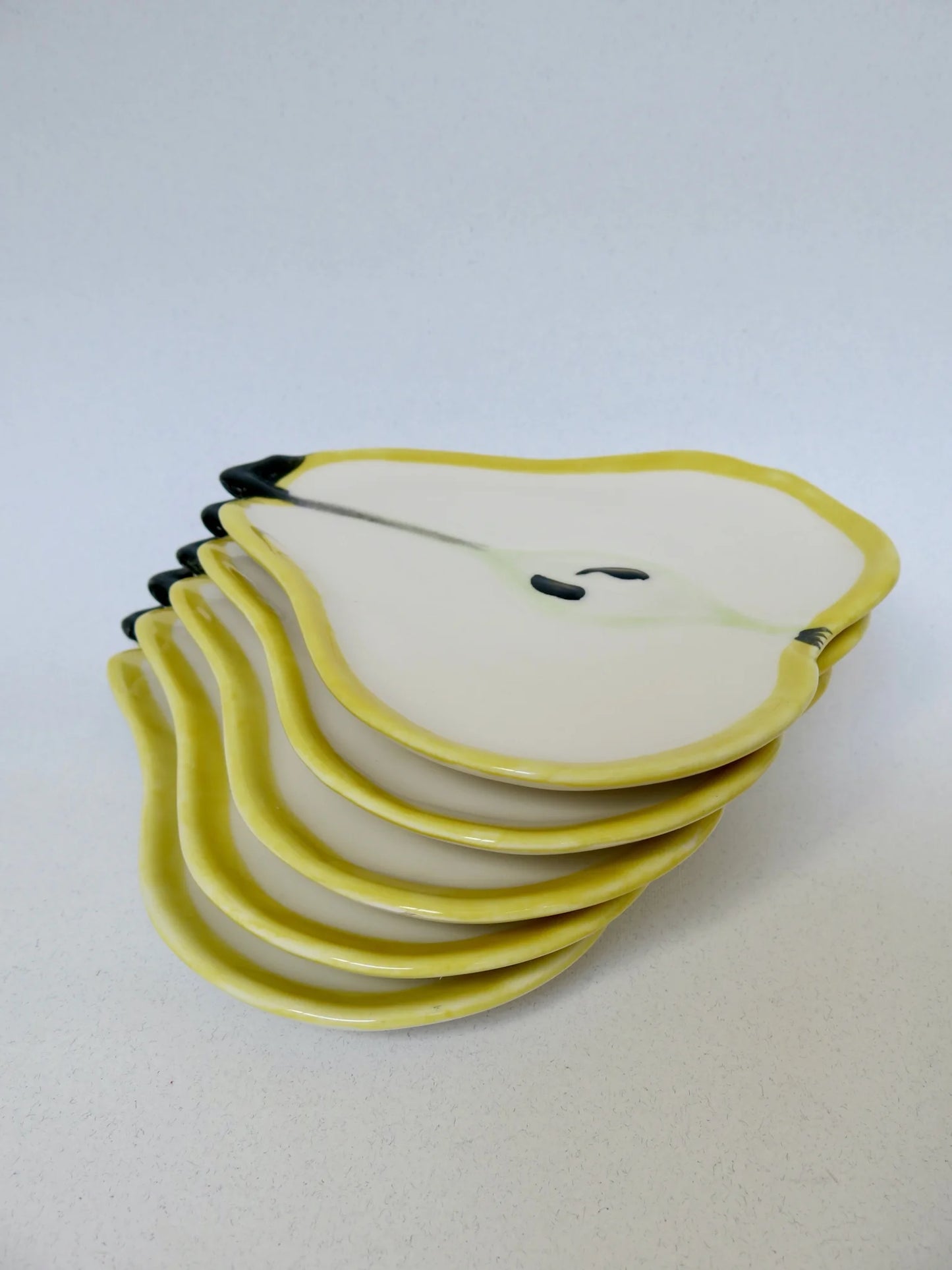 Set piatti M.A.C. a forma di pera – pila vista dal lato con bordo giallo