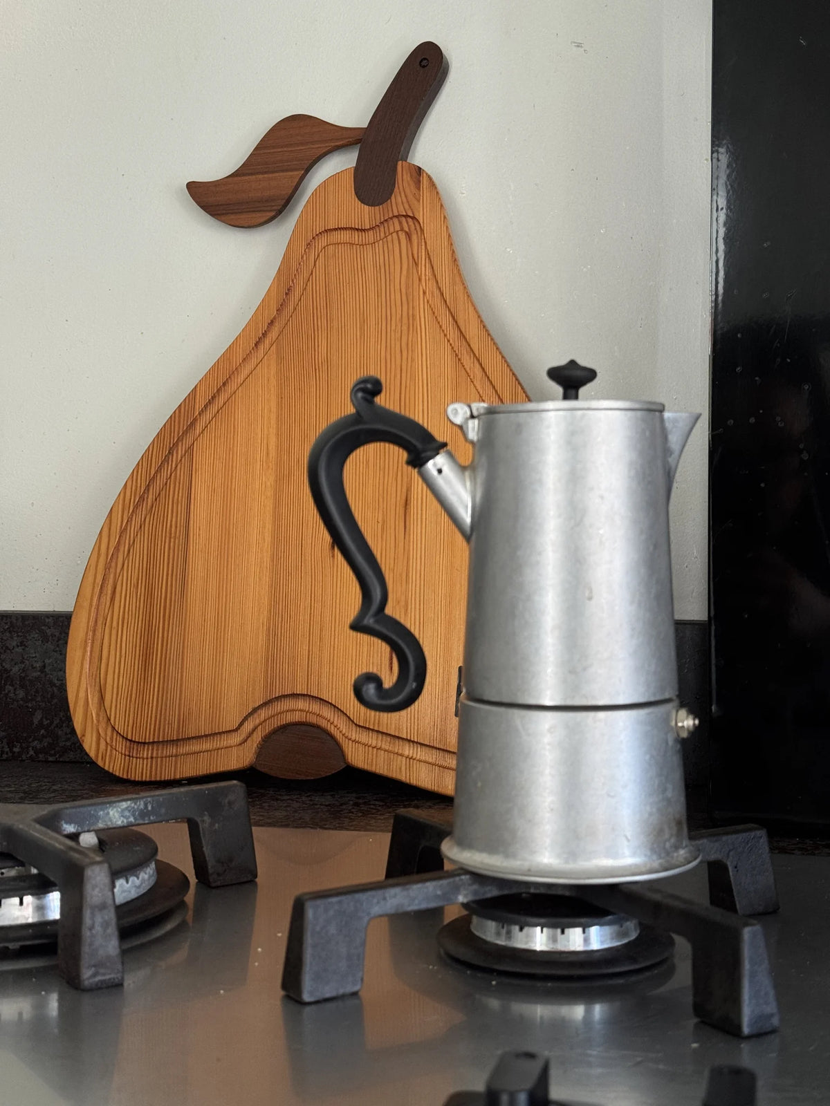 Vassoio in legno a forma di pera Artek Made in Italy – posizionato dietro i fuochi di una cucina moderna